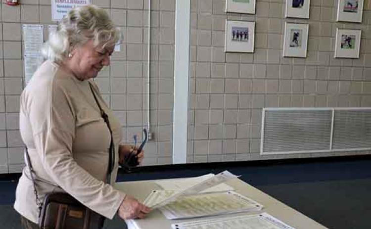 Pattie Rollins takes a look at sample ballots available at the entrance to the Ruby Fulbright Aquatic Center before voting Monday afternoon. (Samantha Sinclair/Staff)