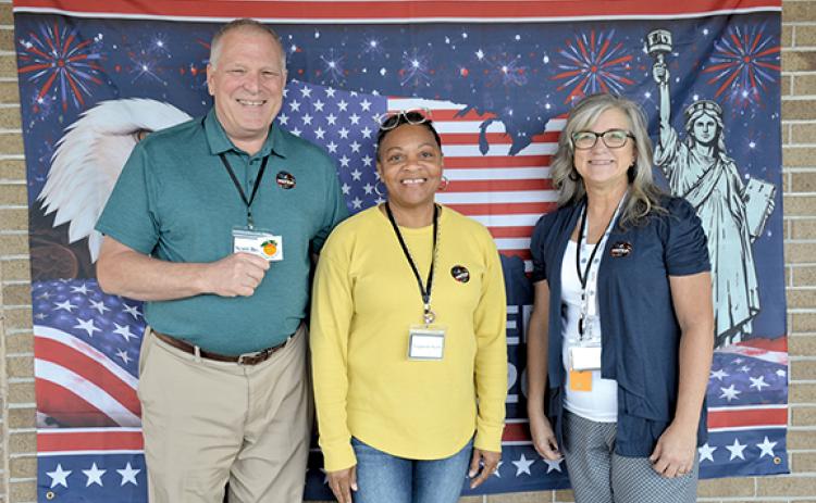 Poll workers Scott Brown, Laqueda Scott and Stephanie Martin show off the ‘I voted’ stickers available for voters at the selfie station set up at the elections office. (Samantha Sinclair/Staff)