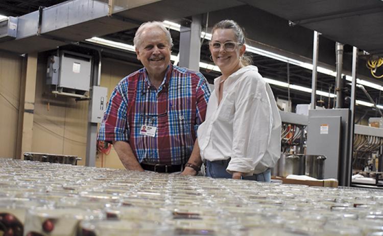 Rush Mauney poses with his daughter, Jessamine Cantey, as candles come down the production line at GlobalTech last year. (Samantha Sinclair/Staff)