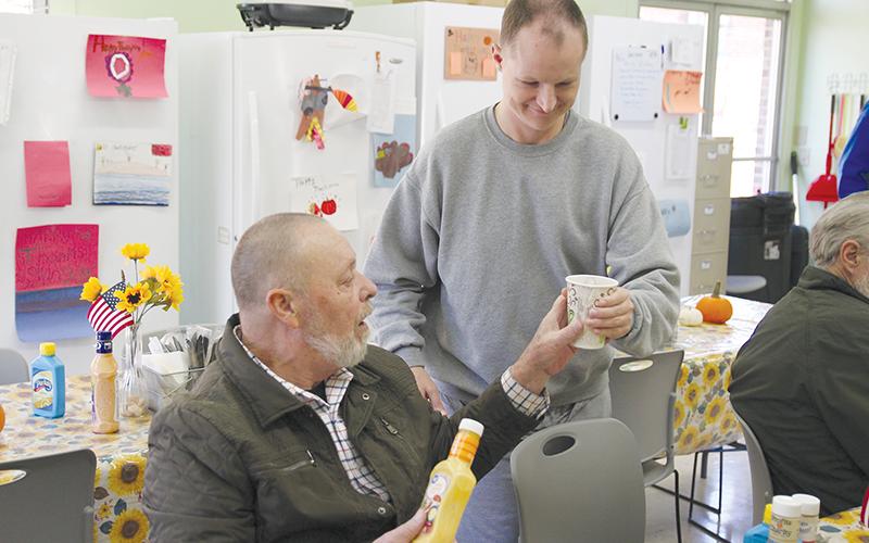 Michael Parks, right, brings a beverage to Bruce Fry of Clarkesville at the Clarkesville Soup Kitchen on Monday afternoon.
