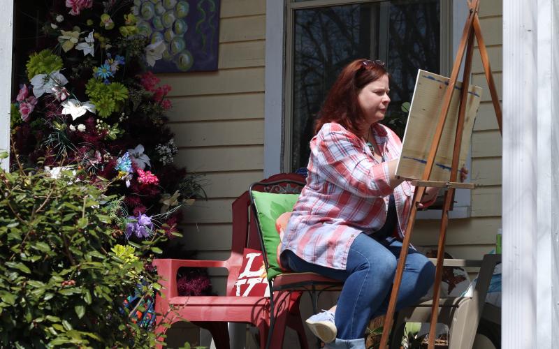 Amy Sullivan paints on the front porch of Canvas and Cork, a wine tasting room and art gallery located on the corner of Dahlonega’s downtown Hancock Park. PHOTO BY CAITLIN JETT