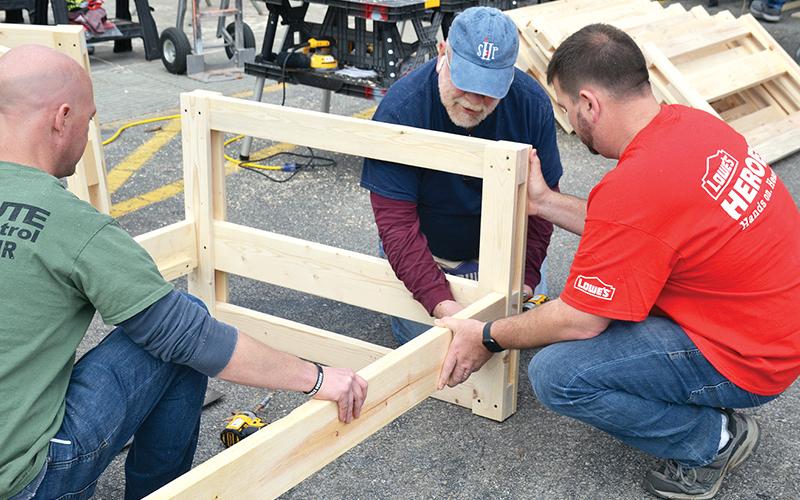 Volunteers Jason Grooms (left), Skip Sevier and Jeremy Gattis assemble the first of 20 bunk beds built Saturday by Lowe’s volunteers in conjunction with the charity Sleep in Heavenly Peace.