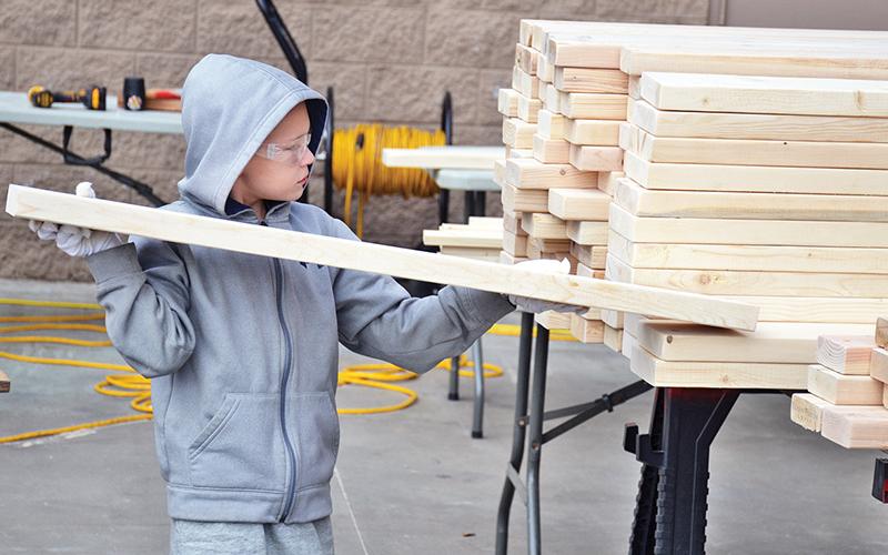 Landon Weaver, 9, of Cornelia helps stack boards in which he marked drill holes Saturday to help build the bunk beds for children in need.
