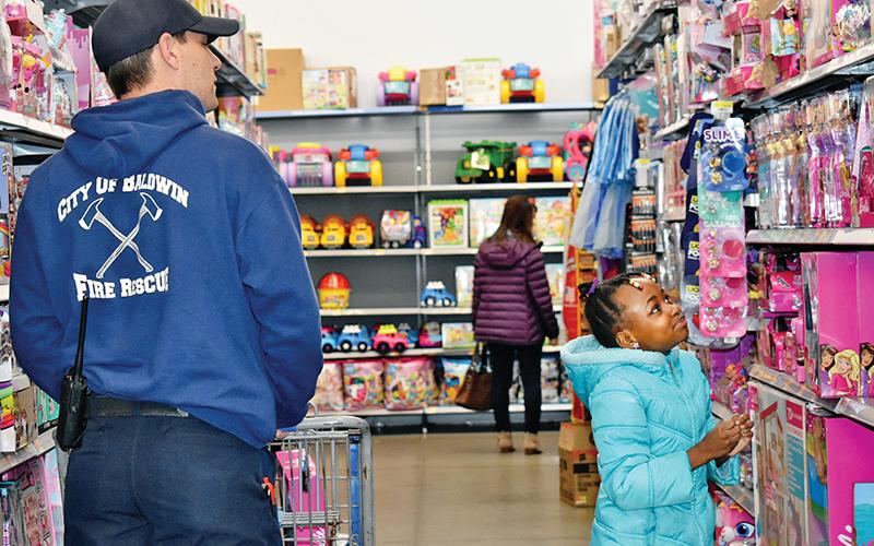 Zykia Grimes, 8, and Joshua Defoor with the Baldwin Fire Department try to decide on a doll Thursday morning. Grimes was one of 15 children that participated in Baldwin's annual Shop With a Hero. This year, each child had a $300 limit to spend on toys, clothes or anything else they wanted. 
