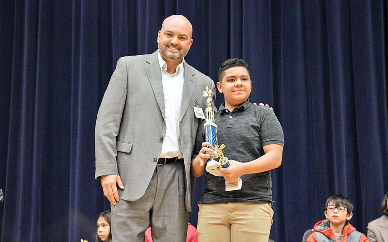 Habersham County Superintendent Matthew Cooper presents Richard Navarro with his trophy at the county spelling bee Wednesday morning.
