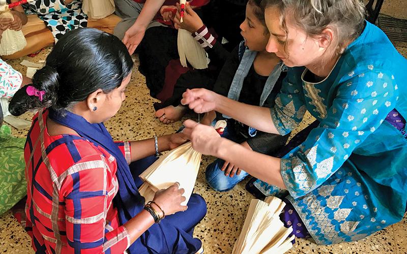 Sarah Samsel (right) teaches children in India how to make corn husk dolls during her mission trip in January.