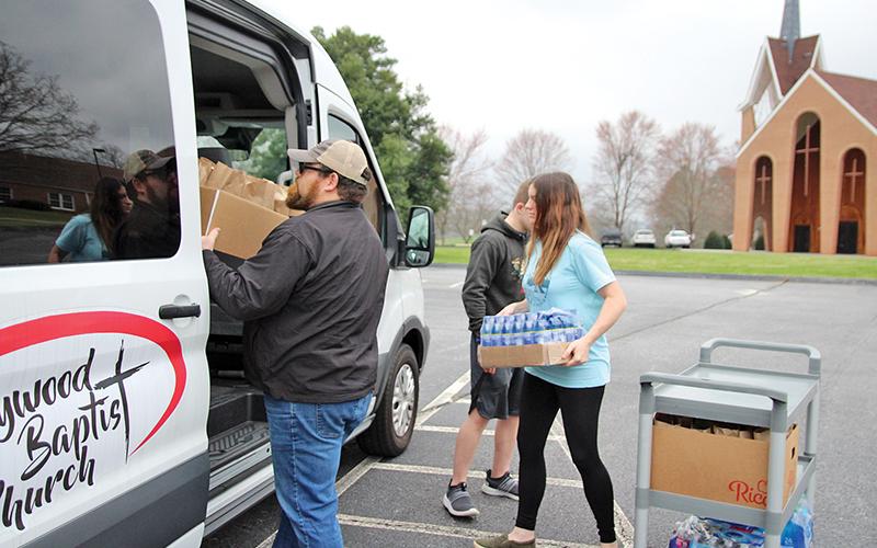 Chuck Johnson with Hollywood Baptist Church, Nathan Rhoads and Jessie Smith with Bethlehem Baptist load up a van with sack lunches that were distributed to families Monday.