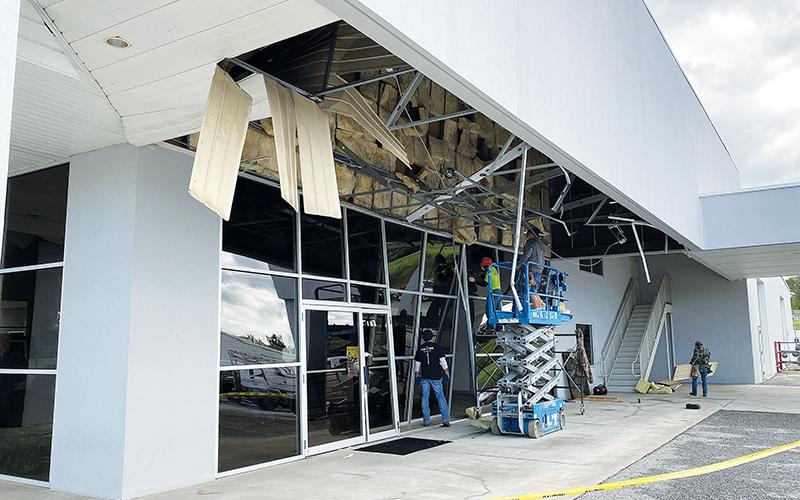 Workers tend to the damage at Hayes auto dealership in Baldwin Monday morning.