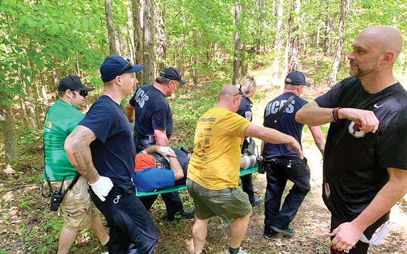 Habersham County EMTs help carry Commissioner Dustin Mealor out of the woods after he suffered a serious foot injury while mountain biking last weekend.