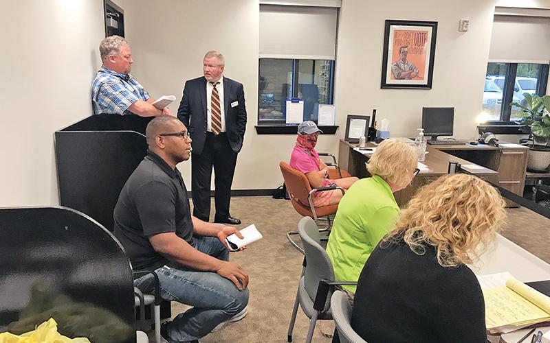Trent Davis (seated left) listens to the Board of Elections’ announcement of the recount results Monday night.
