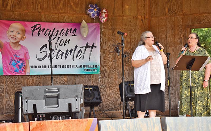 Renee Johnson and Connie Perry sing during the benefit for Scarlett LaCount at Pitts Park on Saturday.