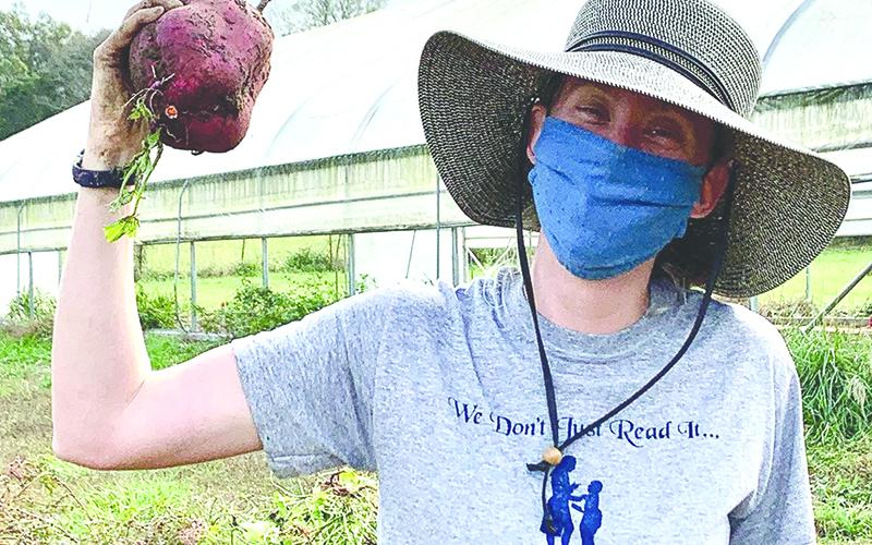 Melon Head Farm Manager Emma Courson shows off a giant sweet potato. Photo courtesy of Joni Kennedy