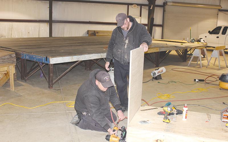 Habersham County Sheriff’s Deputy Jason Eller (left) uses a nail gun to construct a judge’s bench while deputy Paul Jardine (right) holds the wood in place. The pair also constructed a witness stand to be used for superior court in the aquatic center.
