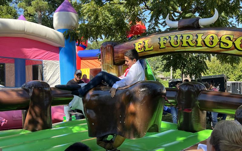 Jonah Maldonado, a local fifth grader, rides a mechanical bull at the festival, which also had bouncy houses for the entertainment of children who attended. AMARIS E. RODRIGUEZ/Staff