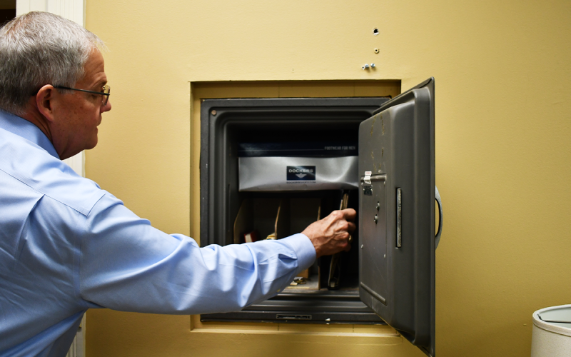 Piedmont President Marshall Criser checks the contents of the secret safe, found while he was redecorating his new office. JOHN DILLS/Staff