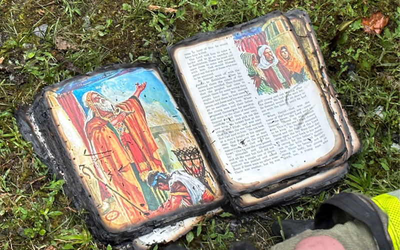 A Habersham County Emergency Services firefighter looks at a Children’s Bible recovered from the burned outbuilding on Hosanna Lane. HABERSHAM COUNTY/Submitted