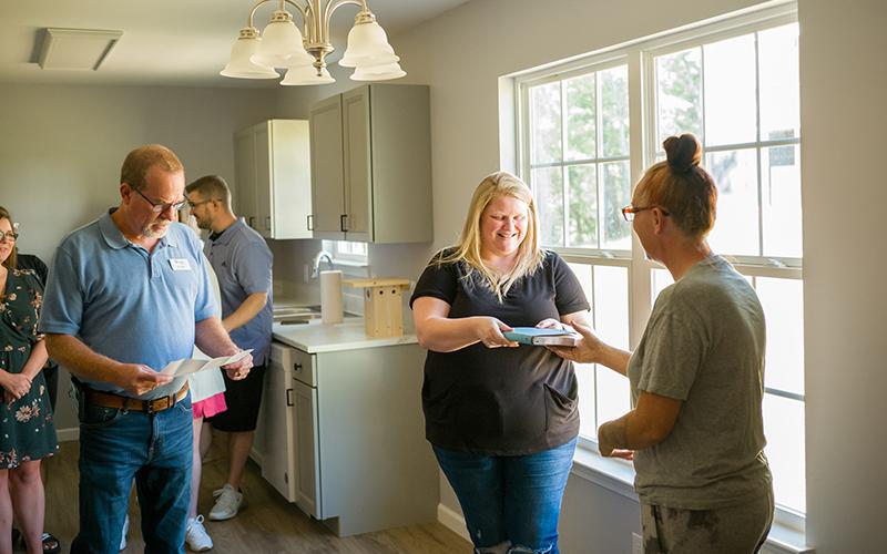 Owner of the most recent Habitat for Humanity home, Lisa Thomas (right), presents Jennifer Payne (center) a Bible and well wishes for her new home. ZACH TAYLOR/Special