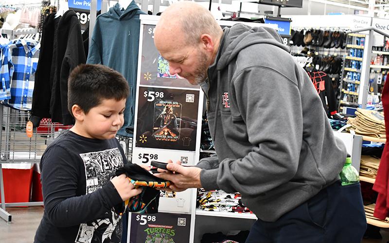 First grader Zayden Tomas Wade picks out a Star Wars T-shirt with Baldwin Fire Chief Joe Roy, organizer of Shop with a Hero. JULIANNE AKERS/Staff