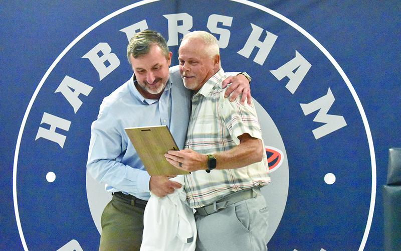 Scooter Garrison (left) gets a hug from his position coach, Mark Ausburn, at Wednesday’s Ring of Honor dinner. MATTHEW OSBORNE/Staff