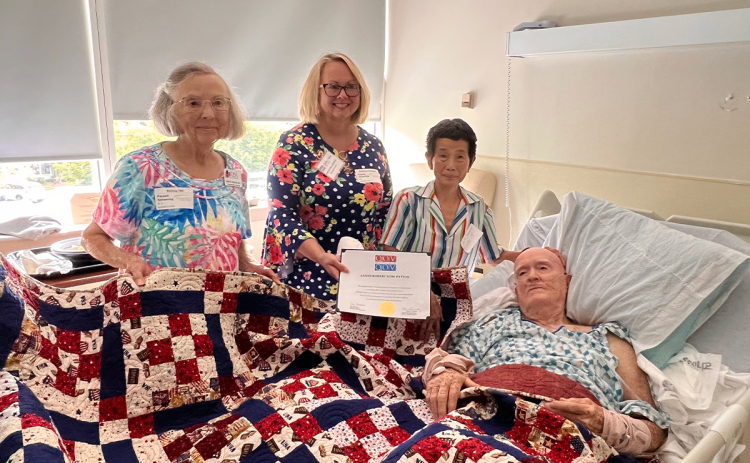 Shirley Hill, member of the Tomochichi Chapter of the National Society of the Daughters of the American Revolution (left), her daughter Rebecca Hill Zuercher (center) and Sheila Patton right, presents the “Quilt of Valor” to Patriot James Robert (Jim) Patton of Clarkesville. RON HILL/submitted