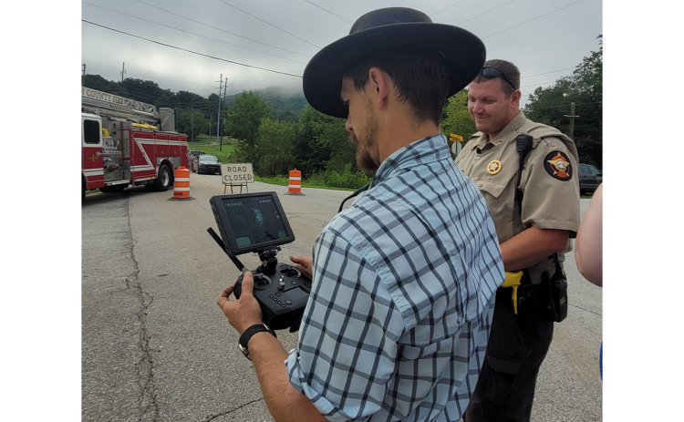 Rabun County Search and Rescue (SAR) Chief Will McCracken utilizes an Unmanned Aircraft System (UAS) drone to take pictures and investigate the area of a crash where a commercial vehicle carrying “blasting agents” overturned on its side early Tuesday morning at Kellys Creek Road in Rabun Gap. Also pictured is RCSO Corporal Jeffrey Hooper working the scene with other emergency personnel. MEGAN BROOME/The Clayton Tribune
