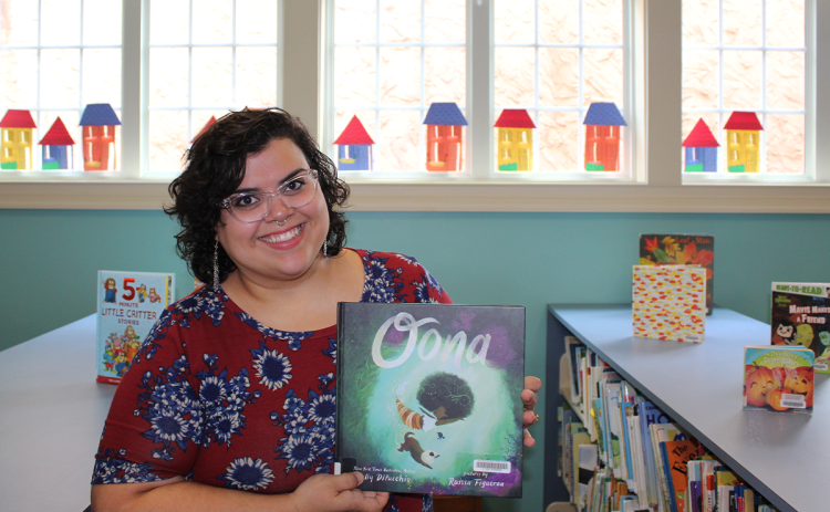 Cristina Irizarry holds up a copy of one of her current favorite children’s books “Oona,” by Kelly DiPucchio, about a little mermaid who is searching for a special treasure. AMARIS E. RODRIGUEZ/Staff