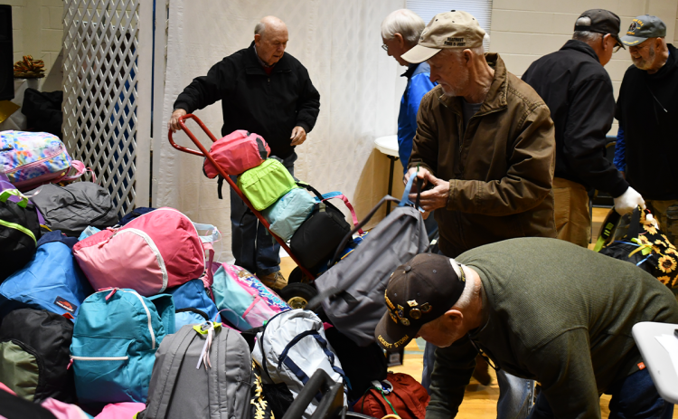 Volunteers (from left) Phil Watson, Tony Gray, Ranny Voight, Larry Lind and Ronnie Conrad help load up backpacks full of food, school supplies and toys for transport to children in need in West Virginia. MATTHEW OSBORNE/Staff