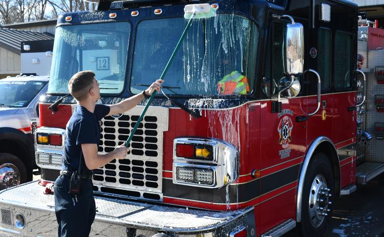 Habersham County Firefighter Isaac Koshiol scrubs the front of the firetruck at Station 12 on Duncan Bridge Road after returning from a call Thursday morning. JOHN DILLS/Staff