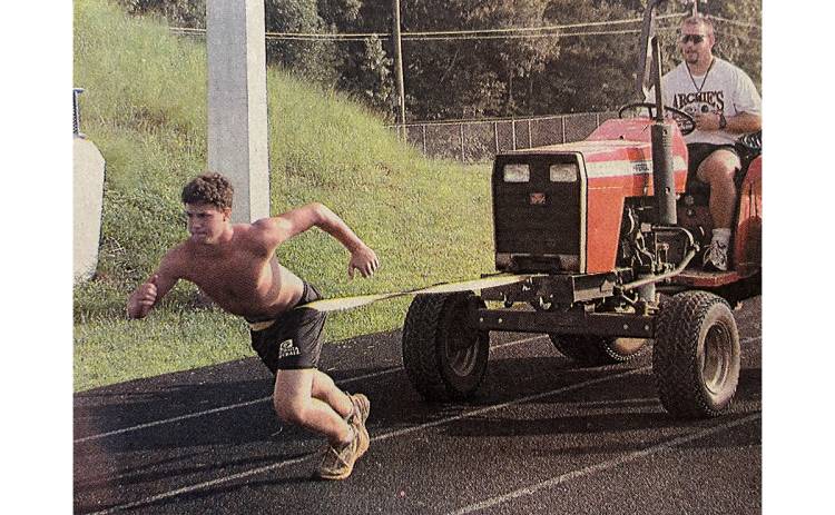 Habersham Central’s Chase Green pulls a tractor containing assistant coach Tim Bragg in 2001 as part of the offseason conditioning program. FILE
