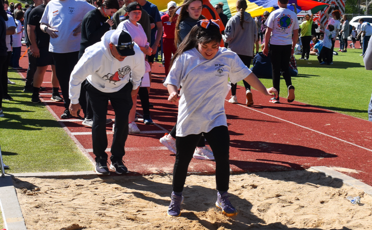 Ninth Grade Academy athlete Fatima Guzman lands in the sand as she participates in the standing long jump during Monday’s Special  Olympics at Raider Stadium. EMMA MARTI/Staff