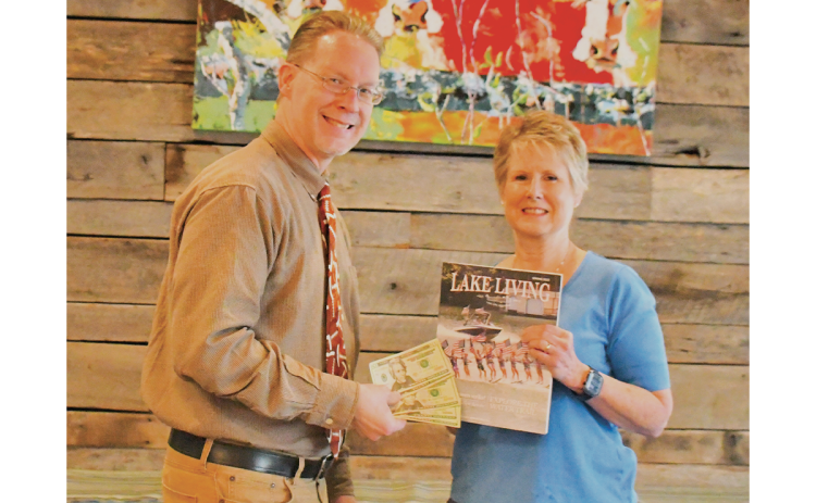 Melissa Elzey won the Spring 2023 Lake Living cover contest with her capture of the Lake Burton Ski Patriots’ performance on July 4, 2021. She is shown getting her prize from Clayton Tribune publisher Enoch Autry. CLAYTON TRIBUNE/Special