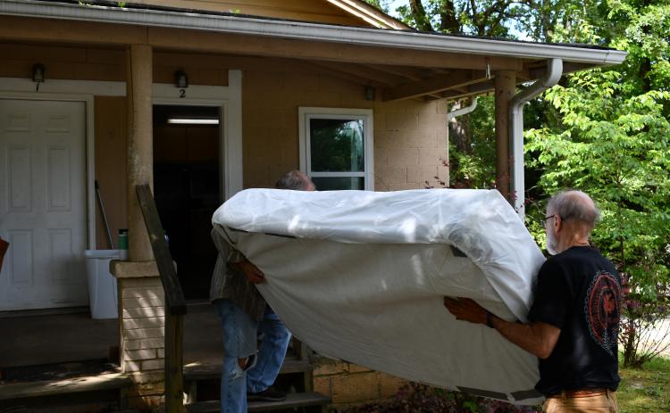 Brad White and Mike Miller bring a mattress inside the home beside Victory Baptist Church. Originally a larger house, the unit was split to accommodate two small families or two individuals. JOHN DILLS/Staff