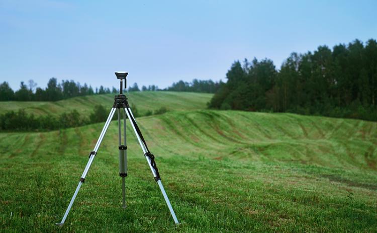 Land surveyor in a field. Valerie V/UNSPLASH